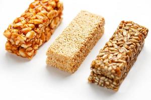 barre de céréales granola avec cacahuètes, sésame et graines d'affilée sur fond blanc. vue de dessus trois barres assorties, isoler photo