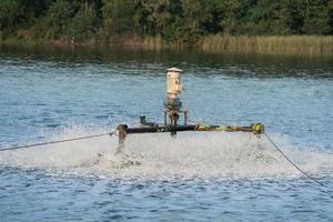 concept de traitement de l'eau. la roue de la turbine de l'aérateur remplit l'oxygène dans l'eau, la vitesse d'obturation élevée capture plusieurs éclaboussures d'eau, sélectionnez la mise au point avec une faible profondeur de champ. conservation du traitement des eaux usées. photo