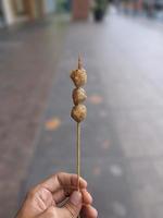 de petites boulettes de viande grillées sont percées et tenues à la main. cuisine de rue locale en indonésie photo