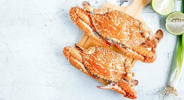 vue de dessus du crabe cuit ou crabe bleu menu fruits de mer crabe cuit à la vapeur sur un fond en bois blanc photo