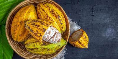 vue de dessus gousse de cacao jaune mûre fraîche et fruit de cacao demi-coupé ouvert sur panier en bambou
