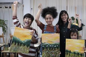 groupe d'artistes dans un studio de classe, un enseignant et des enfants élèves fiers de montrer un travail de peinture, une image en couleur acrylique sur toile, un apprentissage créatif avec des talents à l'école primaire. photo