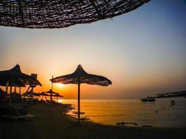 magnifique coucher de soleil sur la plage avec parasols photo