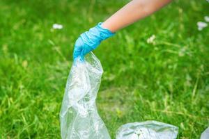 la main de l'enfant nettoie le parc des débris de plastique photo