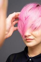 coiffeur vérifiant la coiffure rose de la femme. photo