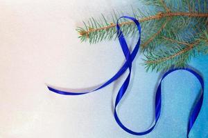 branche d'épinette avec ruban de satin bleu sur fond blanc-bleu. carte noel et nouvel an photo