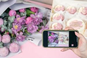 photo au téléphone de cupcakes fraîchement et de belles fleurs sur une table.