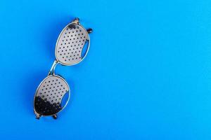 baskets à lunettes. lunettes à sténopé noir sur fond bleu. notion médicale. vue de dessus photo