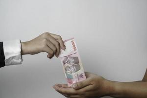 un portrait d'homme d'affaires donnant de l'argent en roupie indonésienne pour un accord commercial ou un paiement ou une œuvre de bienfaisance photo
