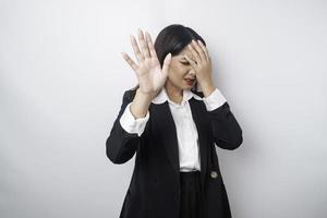 jeune femme d'affaires asiatique isolée sur fond blanc, a l'air déprimée, le visage couvert de doigts effrayés et nerveux. photo