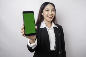 une jeune femme d'affaires heureuse porte un costume noir, montrant l'espace de copie sur son téléphone isolé par fond blanc photo