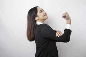 femme d'affaires asiatique excitée portant un costume noir montrant un geste fort en levant les bras et les muscles en souriant fièrement photo