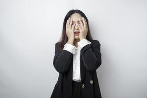 jeune femme d'affaires asiatique isolée sur fond blanc, a l'air déprimée, le visage couvert de doigts effrayés et nerveux. photo