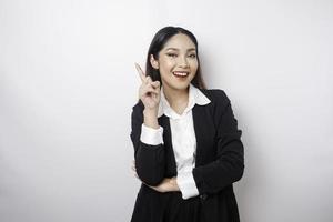 femme d'affaires asiatique excitée portant un costume noir pointant vers l'espace de copie au-dessus d'elle, isolée par fond blanc photo