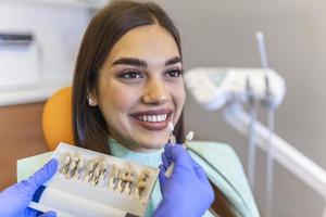 l'ombre des dents du patient avec des échantillons pour le traitement de blanchiment.vu l'hygiène buccale. femme chez le dentiste. femme dans le fauteuil dentaire traitement dentaire pendant la chirurgie. photo