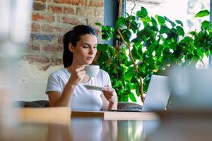 belle jeune femme avec une tasse de café. femme aime le café frais le matin avec le lever du soleil au café belle femme buvant du café le matin assis près de la fenêtre photo