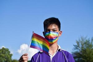 portrait jeune garçon asiatique tient le drapeau arc-en-ciel, symbole lgbt, dans les mains tout en rejoignant son activité lgbt à l'école, concept pour la célébration de la communauté lgbt pendant le mois de la fierté, juin 2023, dans le monde entier. photo