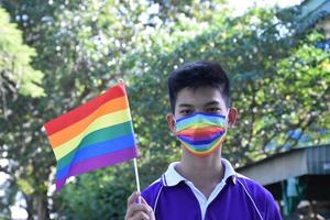 portrait jeune garçon asiatique tient le drapeau arc-en-ciel, symbole lgbt, dans les mains tout en rejoignant son activité lgbt à l'école, concept pour la célébration de la communauté lgbt pendant le mois de la fierté, juin 2023, dans le monde entier. photo