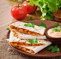 quesadilla mexicaine en tranches avec des légumes et des sauces sur la table