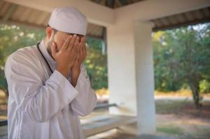 jeune homme musulman asiatique priant au coucher du soleil, concept du festival du ramadan photo