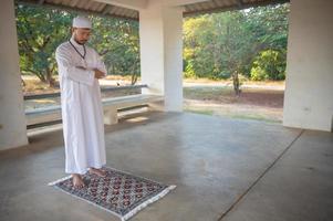 jeune homme musulman asiatique priant au coucher du soleil, concept du festival du ramadan photo