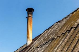 tuyau de cheminée sur le toit de la maison contre le ciel bleu. photo