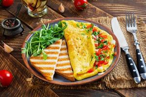 omelette frite aux tomates, oignons et herbes. délicieux petit déjeuner avec des œufs et des toasts