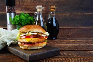 savoureux burger de poulet avec laitue, fromage, tomate et cornichon. sandwich de restauration rapide avec escalope de poulet photo