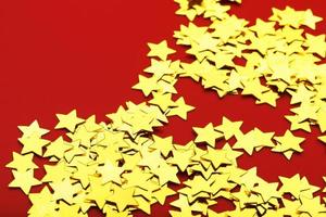 une dispersion d'étoiles dorées sur fond rouge. cartes de voeux, titres et concept de site Web. photo