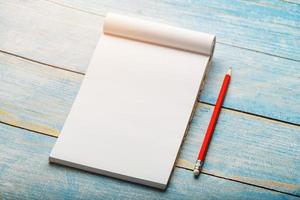 cahier pour écrire avec un crayon rouge sur fond bleu. espace vide libre pour écrire sur une feuille vierge d'un cahier,. photo