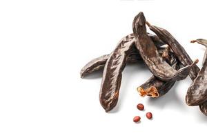 caroube caroube fruits et graines sur fond blanc. isoler. des caroubes bio, une alternative saine au cacao. photo