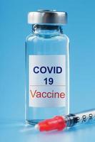 seringue et ampoule avec un vaccin contre le virus covid-19 contre les maladies sur fond bleu. photo