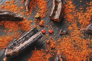 chocolat de caroube et poudre de fruits de caroube sur fond sombre. un substitut savoureux et utile au chocolat. photo