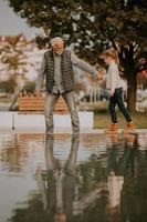 grand-père passe du temps avec sa petite-fille au bord d'une petite piscine d'eau dans le parc le jour de l'automne photo