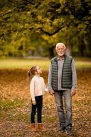 grand-père passe du temps avec sa petite-fille dans le parc le jour de l'automne photo