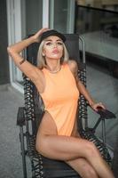 belle femme parfaite en body orange posant devant la caméra .belle blonde mince avec un corps bronzé parfait posé sur un balcon.