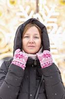 portrait d'une jeune femme chaudement vêtue dans la rue sur fond de décorations de noël par une journée froide et enneigée photo