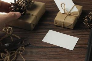 mains masculines emballant des cadeaux de nouvel an et écrivant des cartes sur une table en bois marron. photo