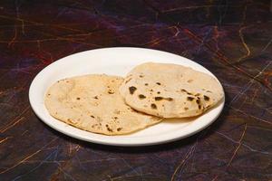 cuisine traditionnelle indienne chapati ou roti, ou pain indien dans une assiette blanche avec de la farine photo