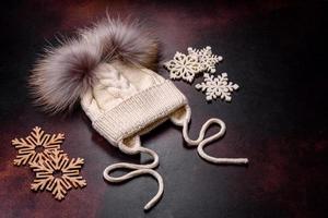 beau bonnet d'hiver tricoté blanc avec pompons sur fond de béton foncé photo