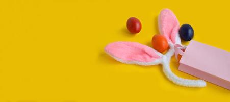 vue de dessus sur un sac rose avec des oreilles de lapin symboles d'oeufs colorés de pâques, traditions. le concept d'achats en ligne pour pâques, d'achats et de ventes en ligne pour les vacances. photo