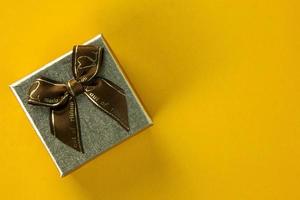 une boîte-cadeau en or avec vue de dessus de rubans sur fond jaune, utilisation d'une boîte-cadeau jaune pour noël et conception d'affiche de concept de bonne année 2023. photo