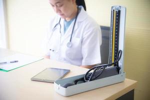 une femme médecin avec des appareils médicaux, un stéthoscope et un tensiomètre vérifie la santé du patient et prend note du livre blanc à l'hôpital ou à la clinique où se trouve l'entreprise de soins de santé photo