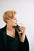 femme élégante et élégante mature en smoking avec un verre de vin mousseux. fête, célébration, concept anti-âge photo