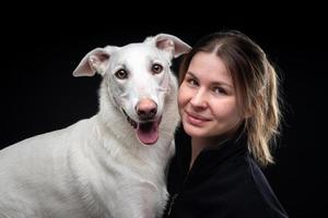 jeune jolie femme pose avec son animal de compagnie blanc, mis en valeur sur fond noir. photo