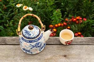 théière chinoise et tasse de thé vert sur une table en bois sur fond de fleurs aux couleurs vives, vue de dessus. pai, thaïlande. photo