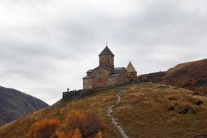 paysage d'automne coloré avec l'église de la trinité gergeti dans les montagnes du caucase, en géorgie. photo