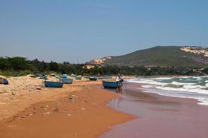 vue sur une plage de sable proche de la mer et d'un village de pêcheurs avec beaucoup d'ordures. pollution d'un littoral. mui ne, vietnam. photo