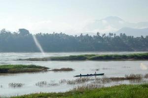 paysage tropical sur le mékong avec bateau, palmiers et montagnes sur la rive au soleil. luang prabang, laos. photo