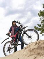 une jeune et jolie femme à bicyclette escaladait une dune de sable, regardant quelque part photo